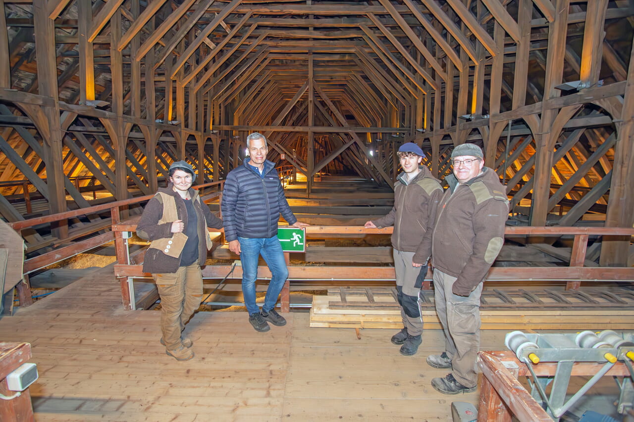 Dombaumeister Gunther Rohrberg (rechts), Steinmetzmeister Thomas Gißke (links) und die Gesellen Jonathan Schulze (Zweiter von links) und Nele Dreizehner stehen direkt unter dem aufgeständerten Kehlbalkendachstuhl. Im Hintergrund, im Osten, ist Gebinde für Gebinde Eiche von 1320 verbaut, das Holz im Westen ist von 1430. Fotos: Thomas Brüggestraße